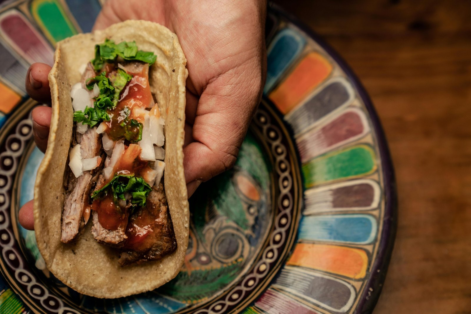 Close-up of a traditional Mexican taco with fresh ingredients on a colorful ceramic plate.